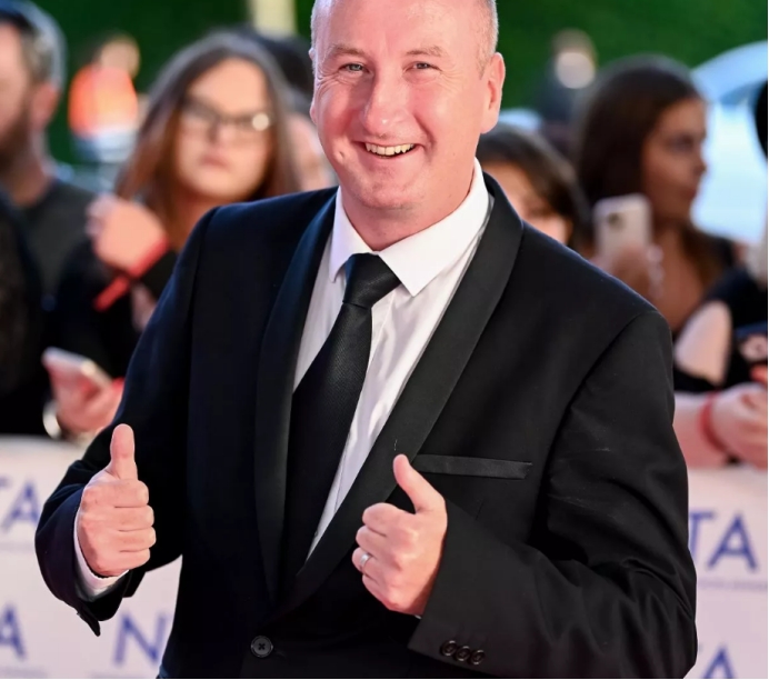 穿着曼联球衣的狂热球迷安德鲁右手拿着*旗国**，密切关注着比赛